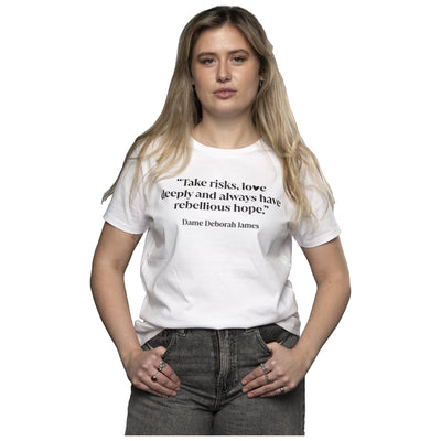 Model wearing Bowelbabe Fund Tight Fit White Tshirt. Take risks, love deeply and always have rebellious hope" on the front with a purple Bowelbabe Fund for Cancer Research UK logo on the back.