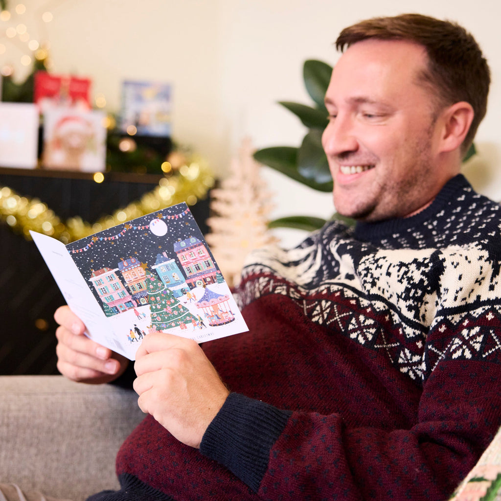 A man is smiling while reading the message inside the Magical Christmas Christmas Card.