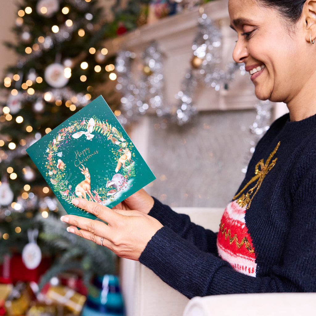 A lady reads the inside of her Winter Wildlife Wreath Christmas Card.