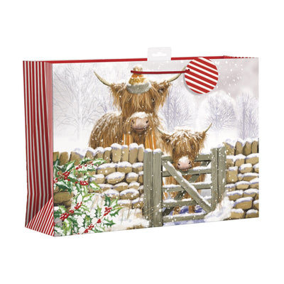 A Christmas-themed gift bag or packaging box featuring an illustration of two Highland cows in a snowy outdoor scene, with red-and-white striped side panels and a hanging loop at the top.
