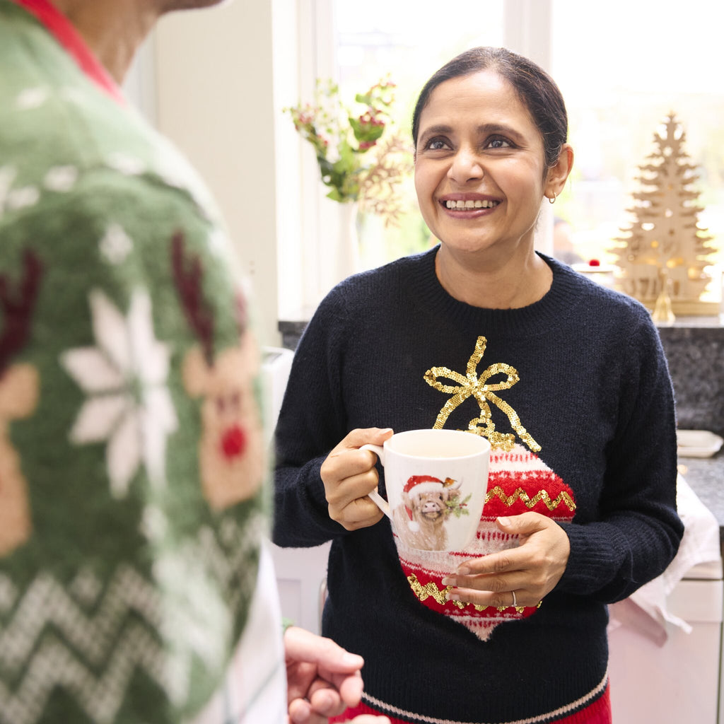 Lady holds Clover Highland Cow Breast Mug in kitchen.