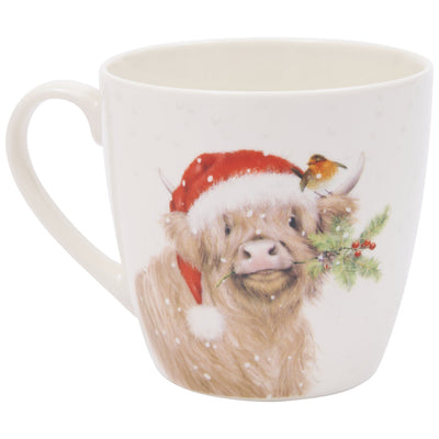 A white ceramic mug featuring a highland cow wearing a red Santa hat with greenery and berries around its horns, and a small bird perched on one horn.