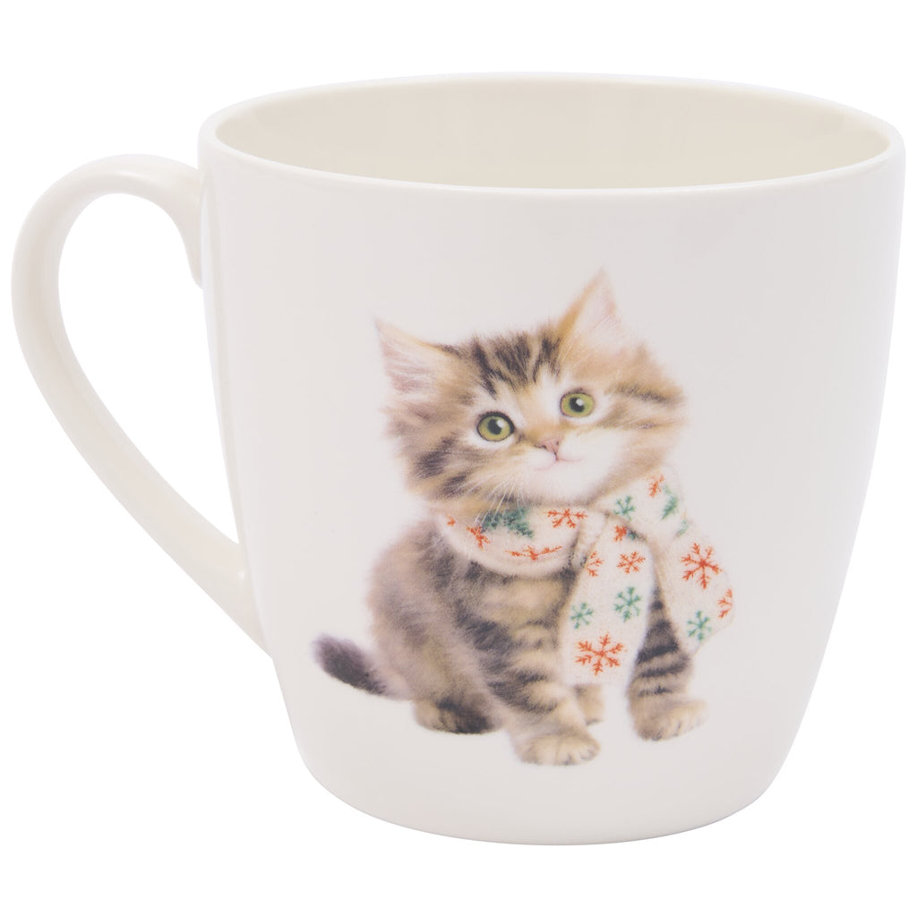 A white ceramic mug featuring a fluffy kitten with green eyes wearing a red and green snowflake-patterned scarf.