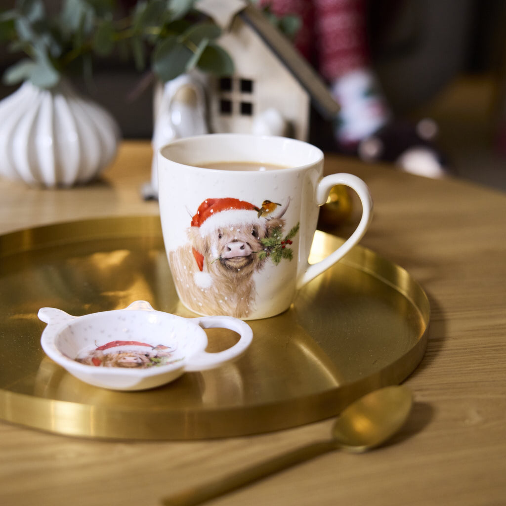 Clover highland cow teabag tidy is in a Christmas environment with a matching mug next to it.