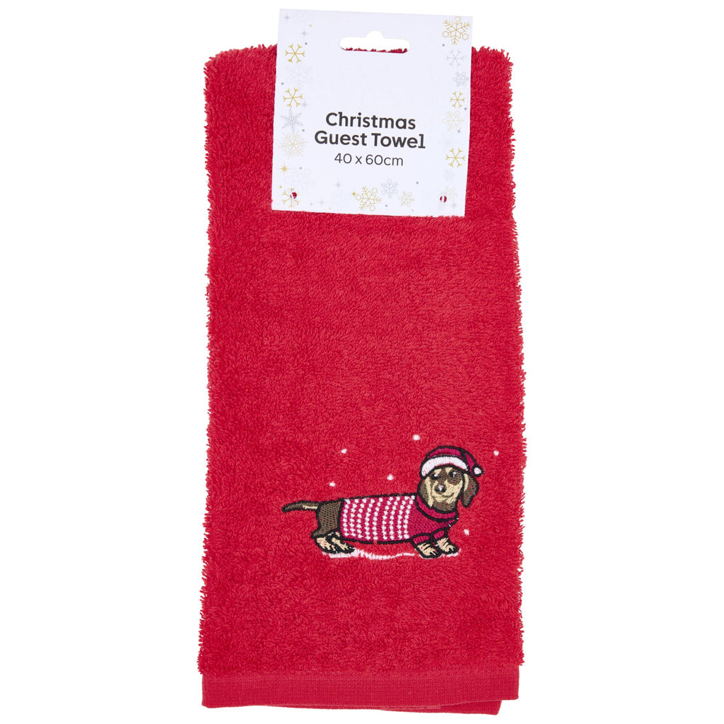 A red guest towel featuring an embroidered dachshund wearing a red and white sweater and a Santa hat, with a label reading "Christmas Guest Towel 40 x 60cm" and snowflake decorations.