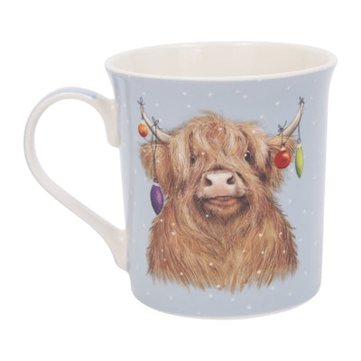 A light blue ceramic mug featuring a detailed illustration of a fluffy Highland cow decorated with colourful Christmas baubles, set against a clean white background.