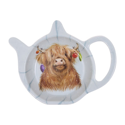 A teapot-shaped ceramic teabag tidy featuring a detailed illustration of a Highland cow with baubles hanging from the horns.