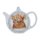 A teapot-shaped ceramic teabag tidy featuring a detailed illustration of a Highland cow with baubles hanging from the horns.