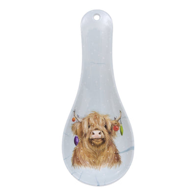A clear glass spoon rest decorated with a painted Highland cow illustration and subtle white speckles, shown against a plain white background.