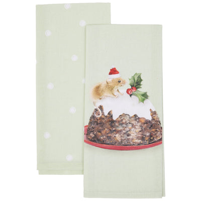 Two light sage green kitchen towels with white polka dots, with the front towel featuring a printed illustration of a small brown mouse wearing a red Santa hat on a white Christmas pudding with holly.