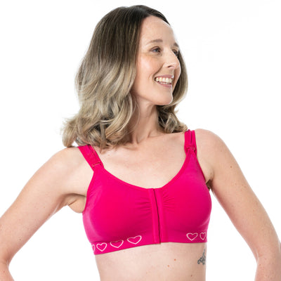 Model shows another angle of the front of the Cancer Research UK Hot Pink Post-Surgery Mastectomy Bra. The easy to use hook and eye closure mechanism is visible to see. Ideal for support and recovery.