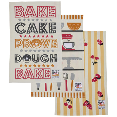 A set of three official Great Stand Up To Cancer Star Baker tea towels, each featuring a different design: one with bold baking-themed words, one with kitchen utensil and mixer illustrations, and one with striped cherries and strawberries.