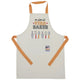 A cream-coloured children's apron with orange neck and waist straps. The chest features the phrase 'mini STAR BAKER' above illustrations of baking utensils. A large front pocket displays a small patch with 'The Great Stand Up To Cancer Bake Off' branding."