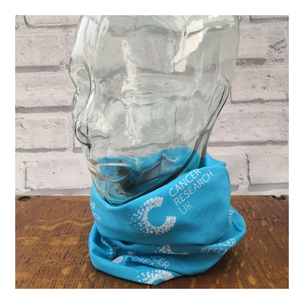 Blue multifunctional snood with Cancer Research pattern displayed on a mannequin head, styled as a neck warmer. Ideal for post-chemo recovery, with soft, breathable fabric that won’t irritate sensitive skin.