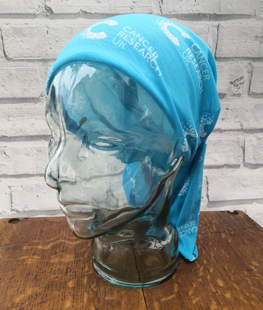 Blue multifunctional snood with Cancer Research pattern displayed on a mannequin head, styled as a full head covering. Ideal for post-chemo recovery, with soft, breathable fabric that won’t irritate sensitive skin.
