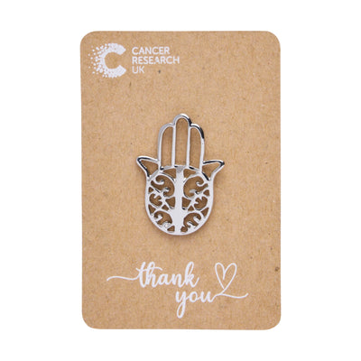 Silver hamsa hand wedding favour on a backing card featuring the Cancer Research UK logo and a thank-you message.
