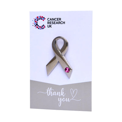 Silver ribbon wedding favour with pink gem on a backing card featuring the Cancer Research UK logo and a thank-you message.