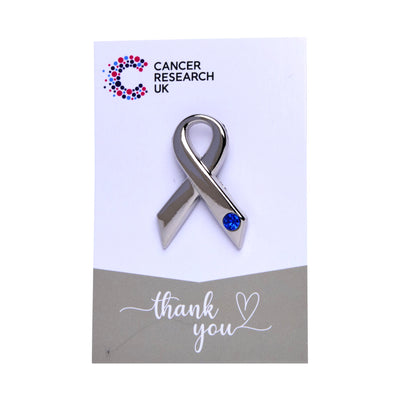 Silver ribbon wedding favour with blue gem on a backing card featuring the Cancer Research UK logo and a thank-you message.