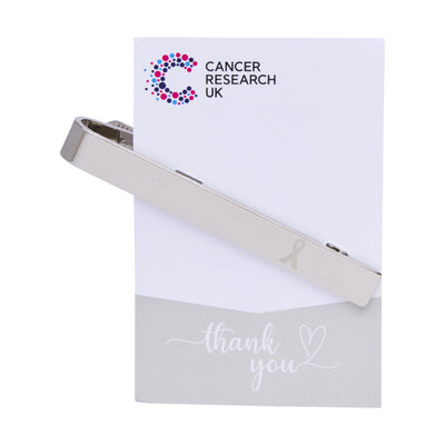 Tie pin wedding favour on a backing card featuring the Cancer Research UK logo and a thank-you message.