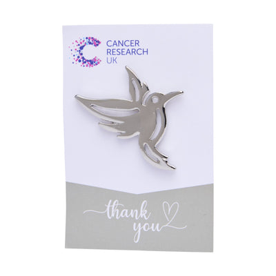 Silver hummingbird wedding favour on a backing card featuring the Cancer Research UK logo and a thank-you message.